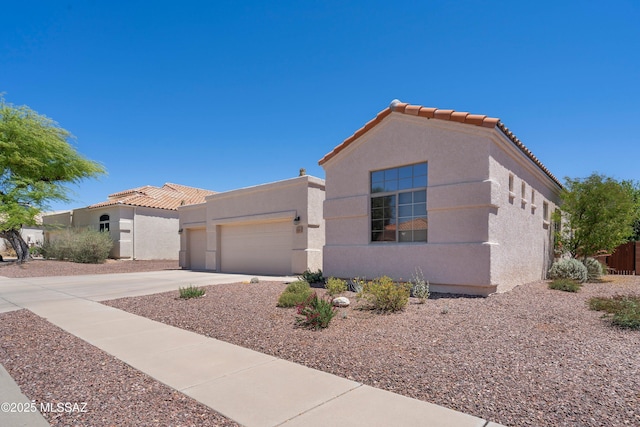 view of front of home featuring an attached garage, stucco siding, a tiled roof, and concrete driveway
