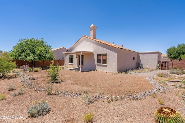 back of house with a fenced backyard, a patio area, stucco siding, and a chimney