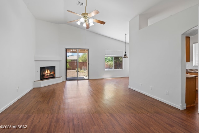 unfurnished living room featuring visible vents, a warm lit fireplace, high vaulted ceiling, arched walkways, and a ceiling fan