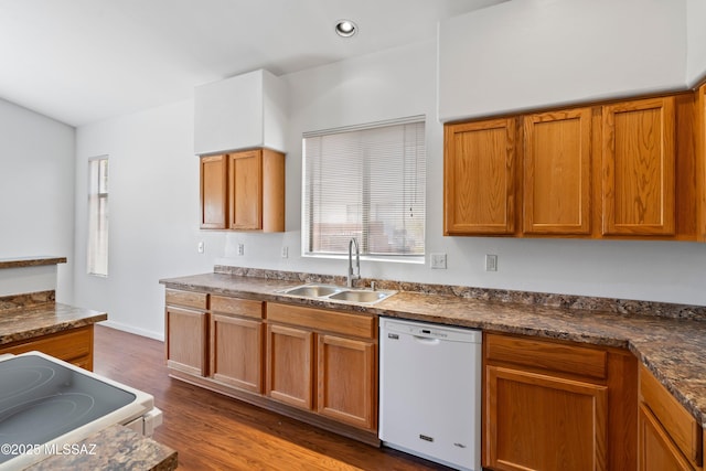 kitchen with brown cabinets, dark countertops, a sink, white appliances, and dark wood-style floors