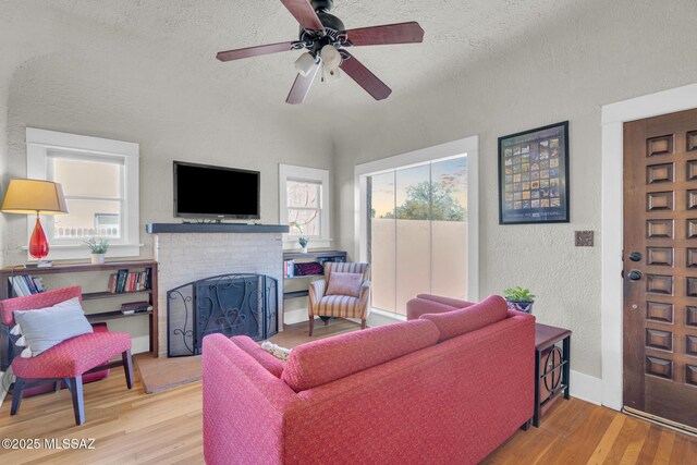 2716 E 6th St, Tucson, AZ 85716 - living area featuring a textured wall, wood finished floors, a fireplace, a ceiling fan, and a textured ceiling
