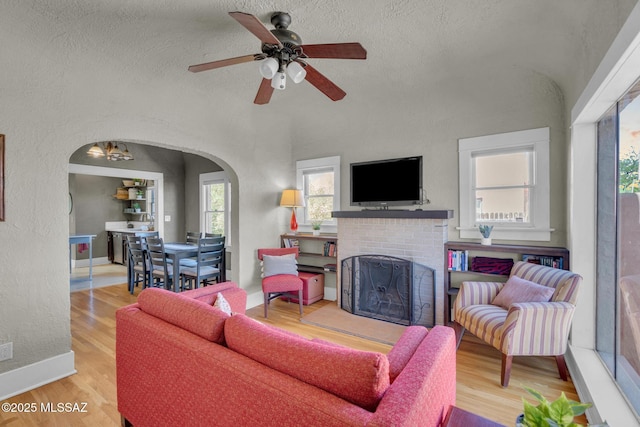 2716 E 6th St, Tucson, AZ 85716 - living area with arched walkways, wood finished floors, a fireplace, ceiling fan, and baseboards