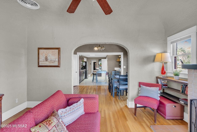 2716 E 6th St, Tucson, AZ 85716 - living room featuring arched walkways, ceiling fan, wood finished floors, baseboards, and a chandelier