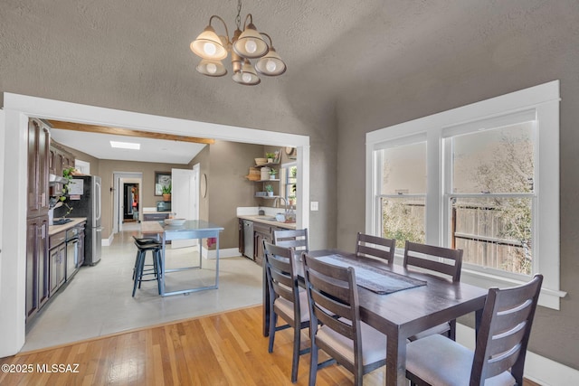 2716 E 6th St, Tucson, AZ 85716 - dining space featuring a chandelier, light wood-style flooring, a textured ceiling, and baseboards