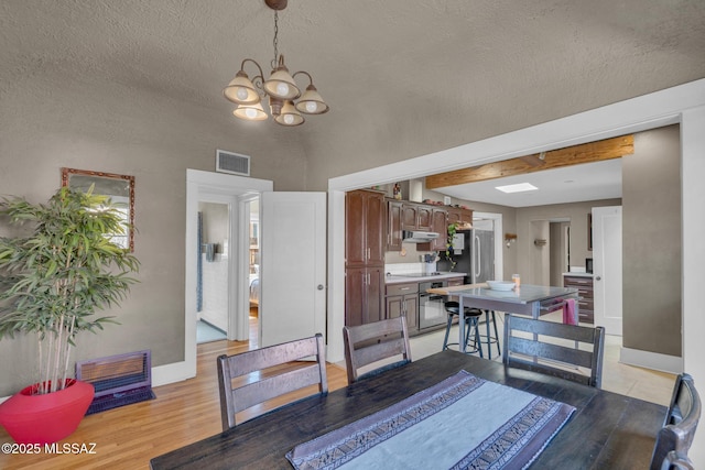 2716 E 6th St, Tucson, AZ 85716 - dining space with a chandelier, baseboards, a textured ceiling, and light wood-type flooring