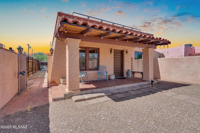 2716 E 6th St, Tucson, AZ 85716 - back of property at dusk with stucco siding, a patio area, and a tiled roof