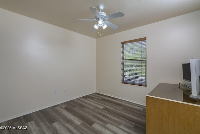 spare room featuring ceiling fan, baseboards, and dark wood finished floors