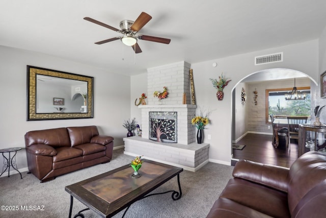 carpeted living room featuring arched walkways, baseboards, a ceiling fan, and visible vents