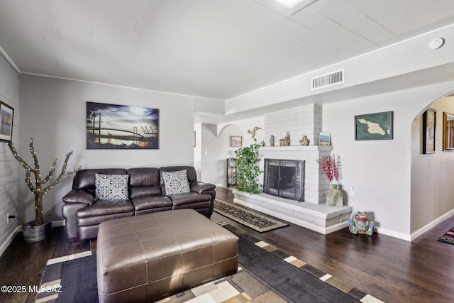 living area featuring arched walkways, baseboards, visible vents, and wood finished floors