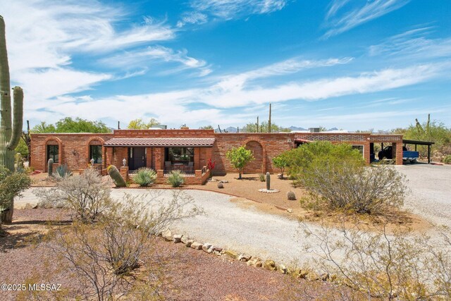view of front facade featuring dirt driveway, an attached carport, and covered porch