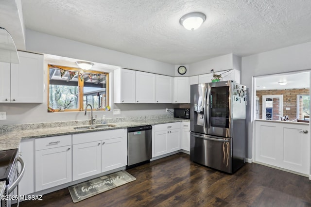 kitchen with dark wood-style flooring, light stone countertops, white cabinets, a sink, and stainless steel appliances