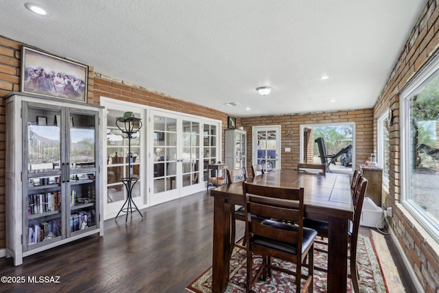 dining space with french doors, a textured ceiling, wood finished floors, and brick wall