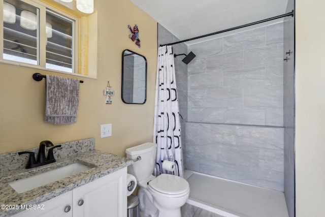 bathroom with vanity, a tile shower, and toilet