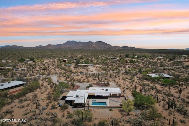 aerial view at dusk featuring a rural view, a mountain view, and view of desert