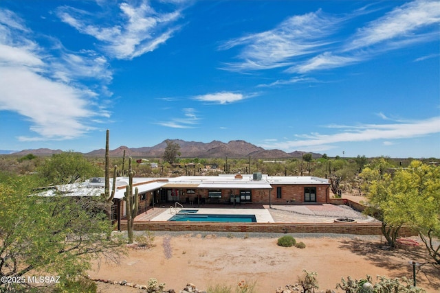 rear view of house featuring a mountain view, a patio, brick siding, and an outdoor pool