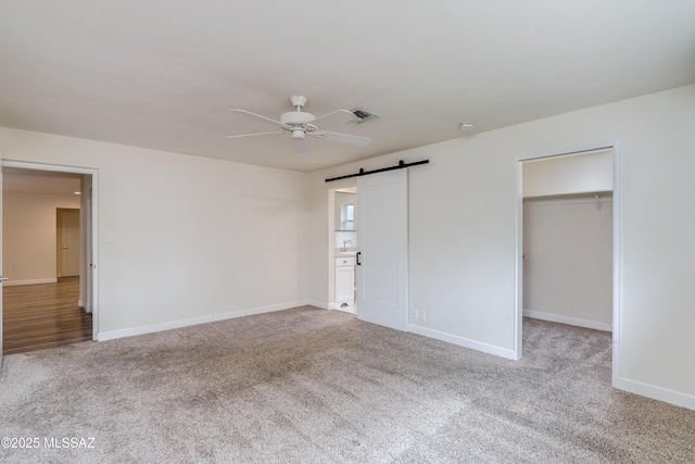 38 N Irving Ave, Tucson, AZ 85711 - unfurnished bedroom with a barn door, a walk in closet, carpet floors, baseboards, and visible vents