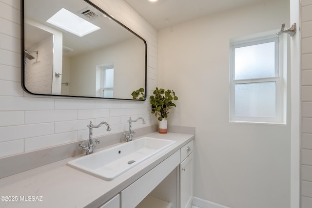 38 N Irving Ave, Tucson, AZ 85711 - bathroom with baseboards, visible vents, vanity, and tasteful backsplash