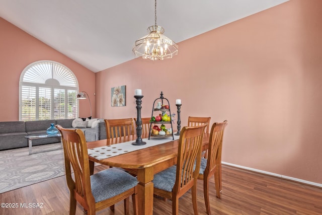 dining area featuring vaulted ceiling, wood finished floors, a chandelier, and baseboards