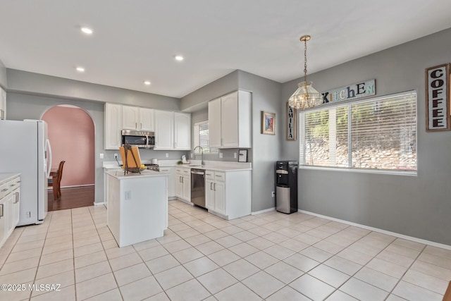 kitchen with white cabinets, a sink, appliances with stainless steel finishes, light countertops, and arched walkways