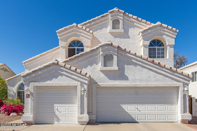 view of front of home with a tile roof, concrete driveway, an attached garage, and stucco siding