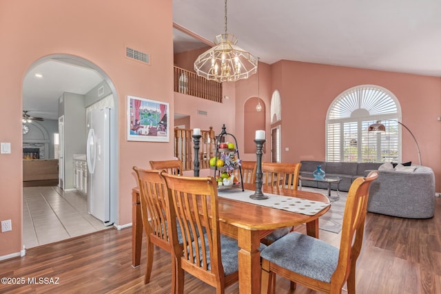 3762 W Meadow Briar Dr, Tucson, AZ 85741 - dining room featuring arched walkways, a chandelier, wood finished floors, a lit fireplace, and baseboards