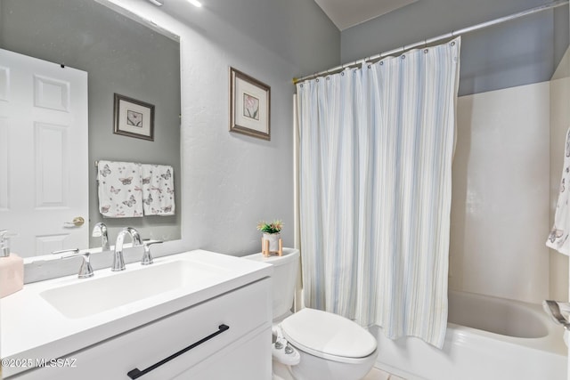 bathroom with shower / bath combo with shower curtain, vanity, toilet, and a textured wall