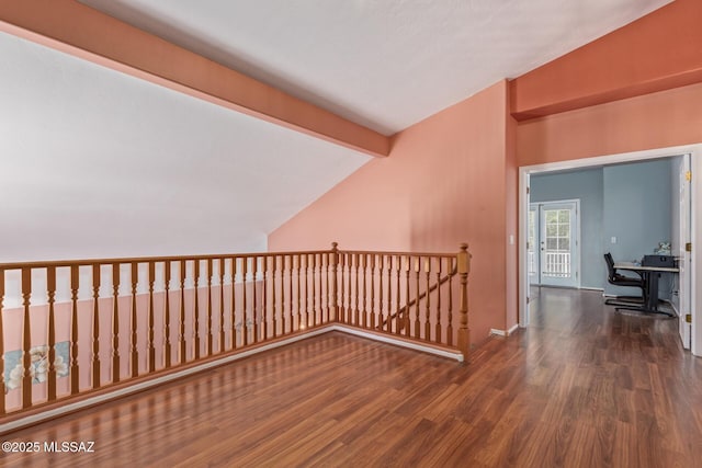 additional living space with baseboards, wood finished floors, and lofted ceiling with beams