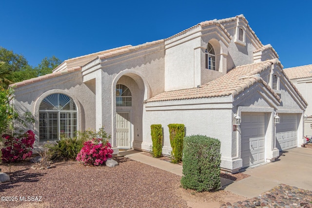view of front of property featuring a garage, stucco siding, a tile roof, and concrete driveway