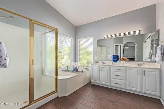 full bath featuring a shower stall, a sink, a bath, vaulted ceiling, and wood finished floors