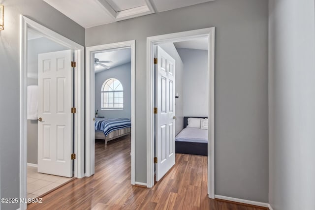 corridor featuring baseboards, wood finished floors, and attic access