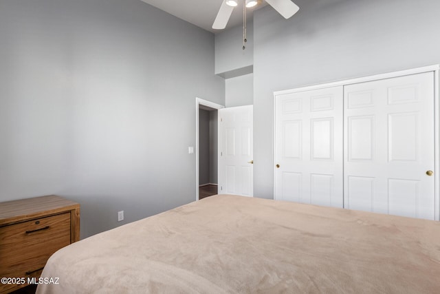 bedroom featuring a ceiling fan, a closet, and a towering ceiling