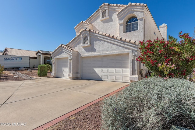 mediterranean / spanish house featuring driveway, a garage, stucco siding, and a tiled roof
