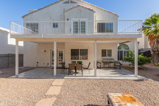 back of house with stucco siding, fence, a patio area, and a balcony