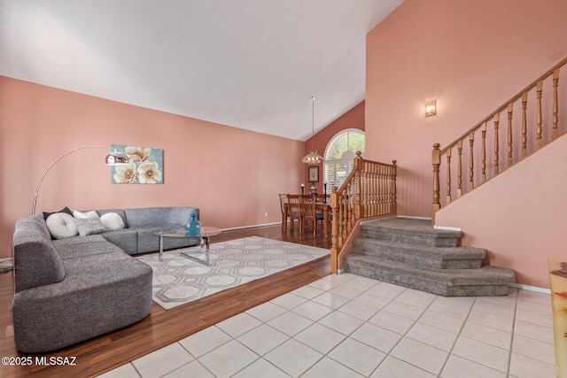 living room featuring a chandelier, baseboards, wood finished floors, high vaulted ceiling, and stairs