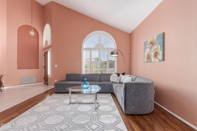 living room featuring wood finished floors, visible vents, high vaulted ceiling, and baseboards