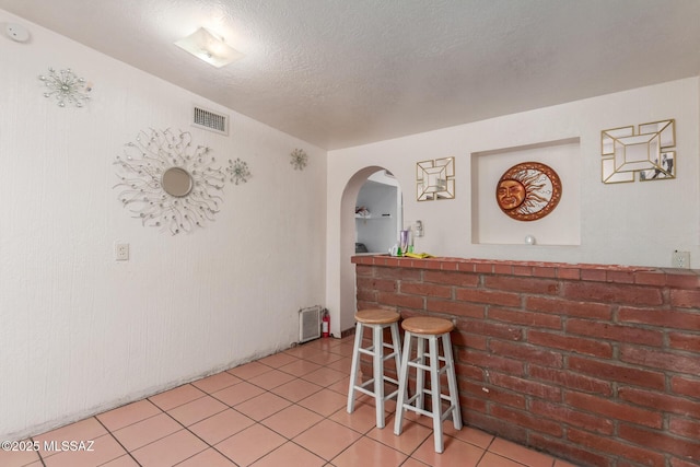 414 E 34th St, Tucson, AZ 85713 - interior space featuring light tile patterned flooring, a dry bar, arched walkways, a textured ceiling, and visible vents