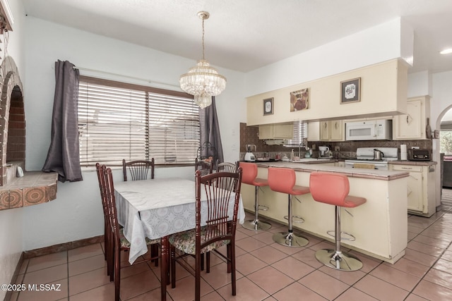 414 E 34th St, Tucson, AZ 85713 - dining space featuring light tile patterned floors, arched walkways, and a chandelier
