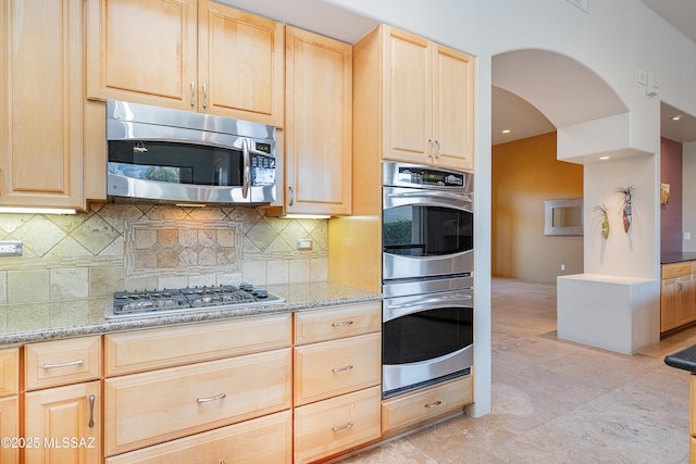 5327 N Ventana Overlook Pl, Tucson, AZ 85750 - kitchen featuring light stone countertops, light brown cabinets, arched walkways, stainless steel appliances, and decorative backsplash
