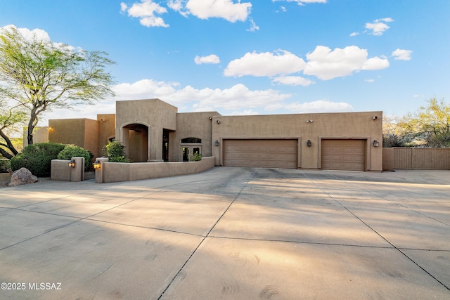 5327 N Ventana Overlook Pl, Tucson, AZ 85750 - pueblo-style house with concrete driveway, fence, stucco siding, and a garage