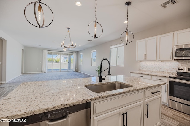 kitchen with appliances with stainless steel finishes, a sink, open floor plan, tasteful backsplash, and visible vents