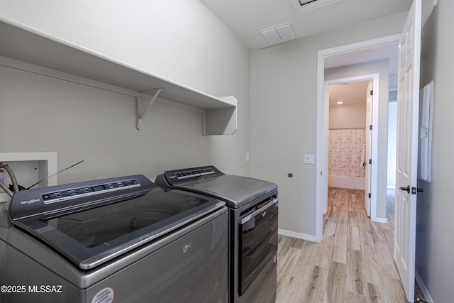 laundry room featuring laundry area, visible vents, washing machine and dryer, light wood-type flooring, and baseboards