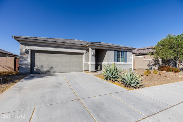 prairie-style house with a garage, fence, stucco siding, a tiled roof, and concrete driveway