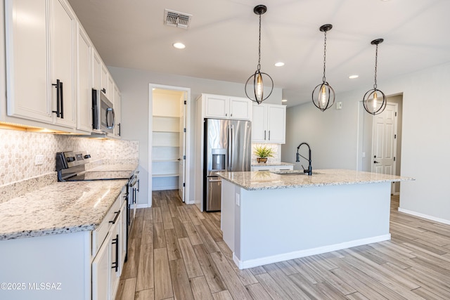 kitchen with backsplash, appliances with stainless steel finishes, a sink, white cabinets, and light wood-style flooring