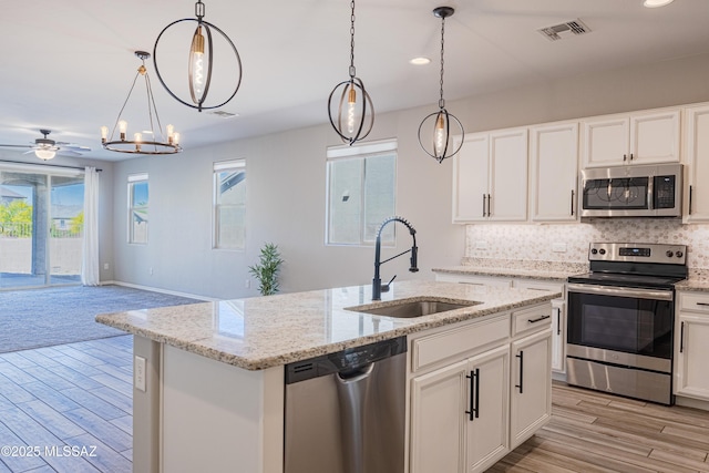 kitchen with backsplash, visible vents, appliances with stainless steel finishes, a sink, and open floor plan