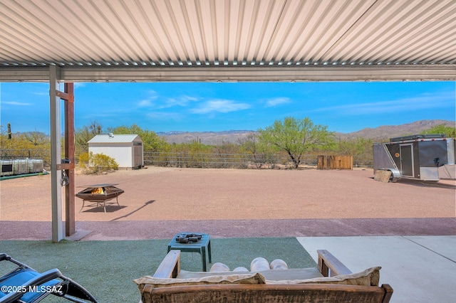 view of patio / terrace with a storage shed, a fenced backyard, a mountain view, and an outdoor structure
