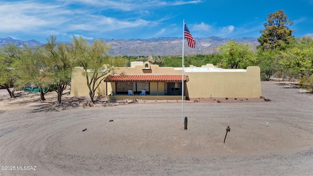 rear view of house featuring a mountain view, stucco siding, and a tiled roof