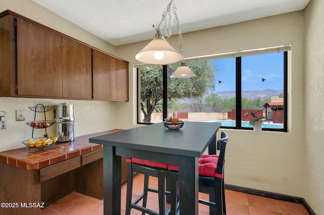 dining space featuring light tile patterned floors, a mountain view, a textured ceiling, and a textured wall