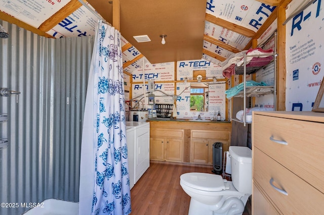 bathroom with washer / clothes dryer, wallpapered walls, toilet, wood finished floors, and vanity