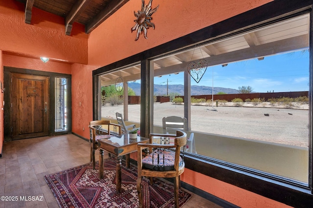 interior space featuring wooden ceiling, beam ceiling, a mountain view, a textured wall, and wood finished floors