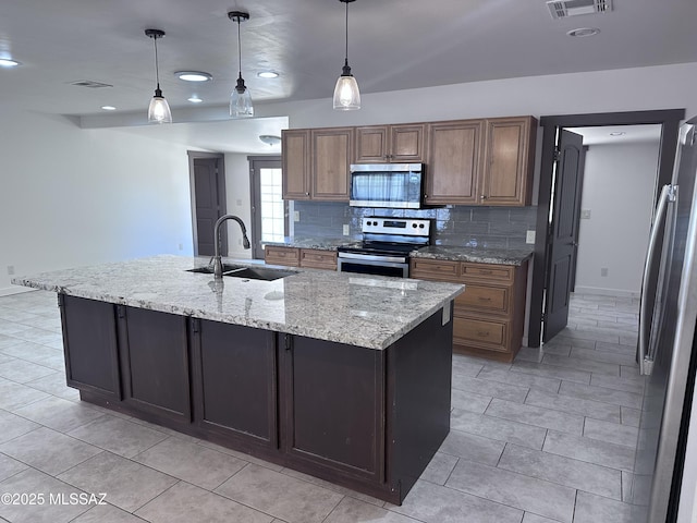 419 N Miller Ln, Saint David, AZ 85630 - kitchen featuring a sink, a center island with sink, backsplash, appliances with stainless steel finishes, and light stone countertops